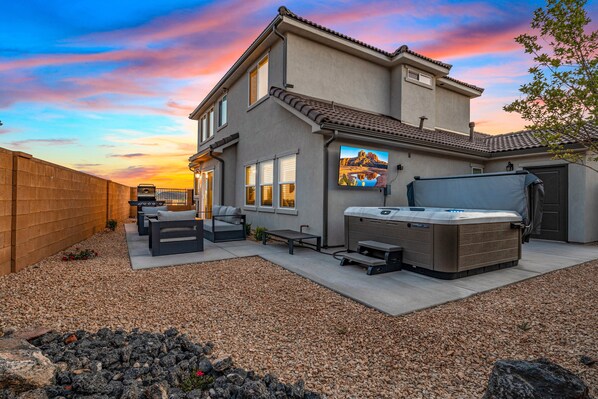 A modern house with a patio, outdoor seating, and a hot tub.