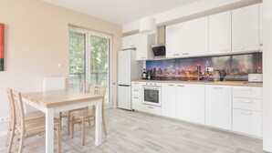 Una cocina moderna con armarios blancos, una mesa de comedor de madera y un salpicadero con vistas a la ciudad.