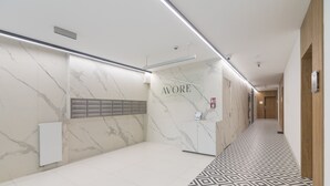 Un pasillo moderno con pared de mármol, un mostrador de recepción con la etiqueta "AVORE" y un suelo estampado.