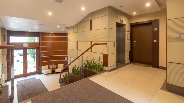 Een moderne hotellobby met een trap, een receptiebalie en een wachtruimte.