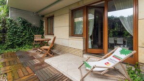Een terras met houten vloer, een tafel, stoelen en een lounge stoel.