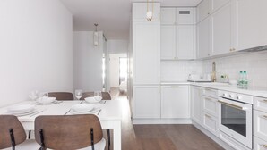 A modern kitchen with white cabinetry, a dining table set for four, and a built-in oven. - Burakowska Pastel Elegant Apartment (Warszawa)