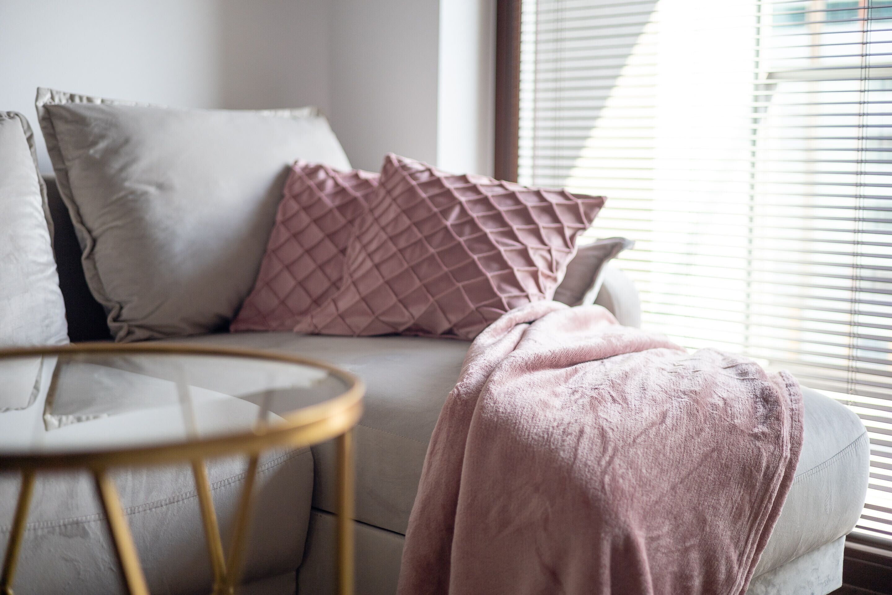 Un salon moderne avec un canapé, des coussins et une couverture.