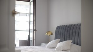 A hotel room with a bed, a bedside lamp, and a view through an open door. - Burakowska Pastel Elegant Apartment (Warszawa)