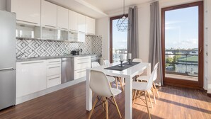 Una cocina moderna con armarios blancos, encimera negra y un comedor con mesa y sillas blancas.