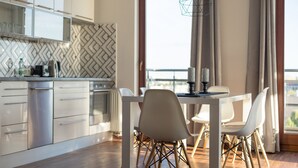 Una cocina moderna con armarios blancos, un salpicadero tipo espiga y un comedor con una mesa y sillas blancas.