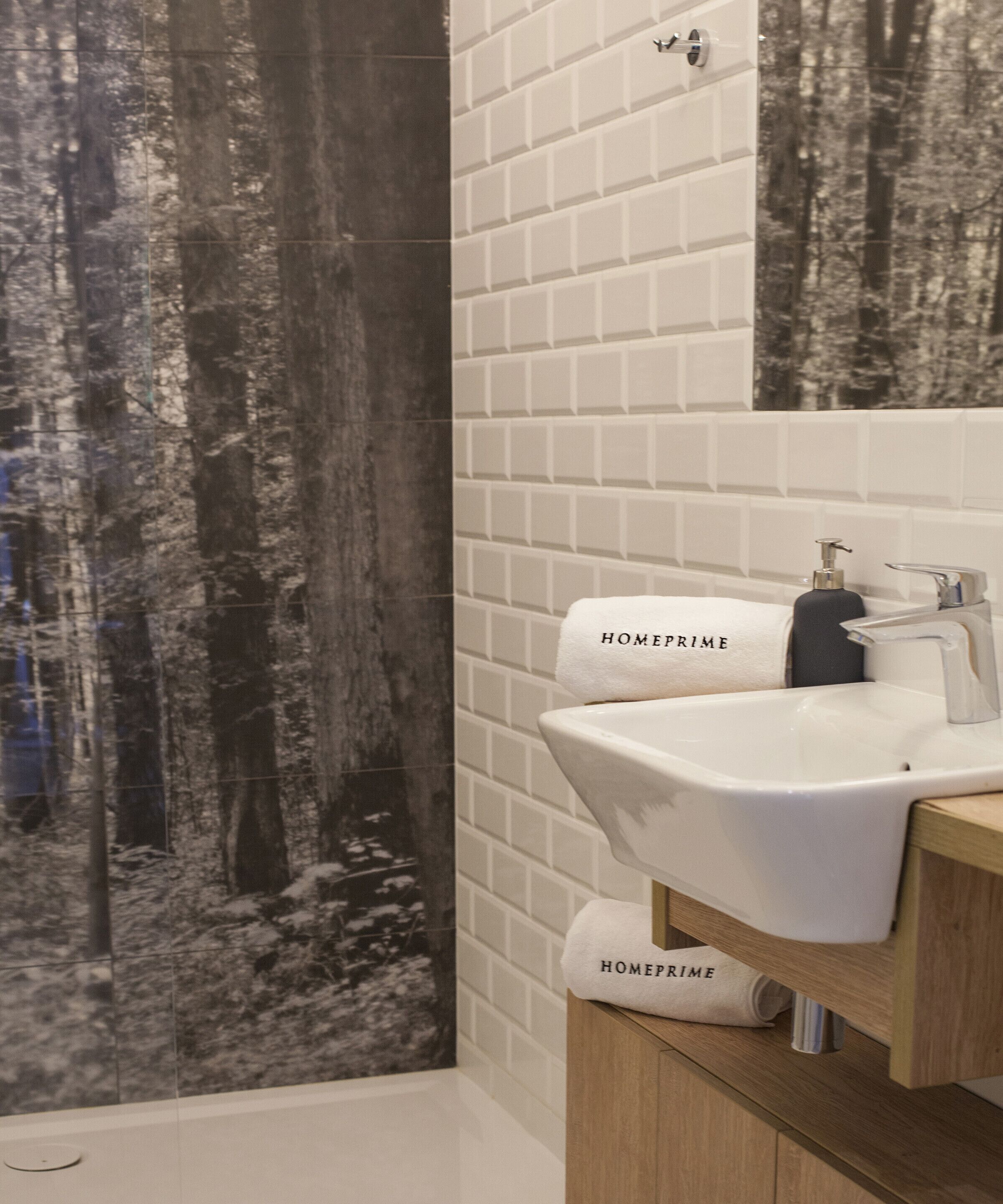 Un baño con lavamanos blanco, un espejo y un perchero con la etiqueta 'HOMEPRIME'.