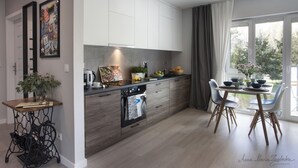A modern kitchen with a built-in oven, a dining table with chairs, and a large window with curtains.