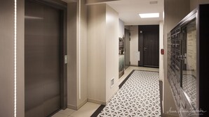 A modern hallway with an elevator, patterned floor, and lockers.