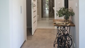 A hallway with a wooden table, a potted plant, and a shower area.
