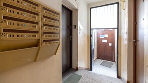 A hallway with numbered mailboxes, a door, and a view of the outside.