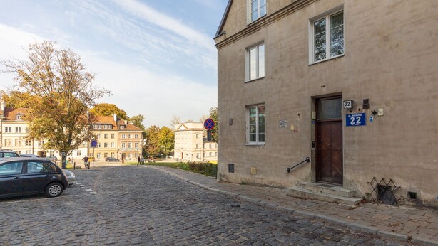 A cobblestone street with a building marked '22' and a parked car.