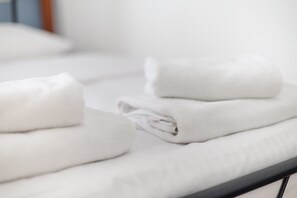 Neatly folded white towels stacked on a bed. - Brzozowa Old Town Square Studio (Warszawa)