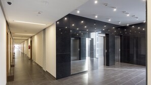 A modern hallway with a long corridor, black marble walls, and a tiled floor.