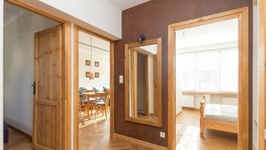 A room with wooden flooring, a bed, a large mirror, and a window with blinds. - Piękna 2-Bedroom Apartment (Warszawa)