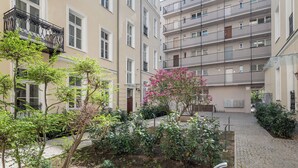 A courtyard with a paved walkway, surrounded by multi-story buildings with balconies and windows. - Piękna 2-Bedroom Apartment (Warszawa)