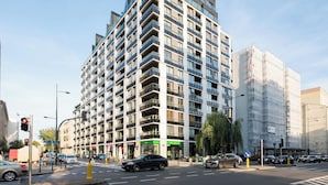 Un hotel de varios pisos con balcones, un restaurante en la planta baja y un paso de peatones.