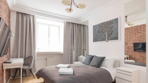 A modern bedroom with a bed, a desk, and a chair. - Old Town Grey Apartment (Warszawa)