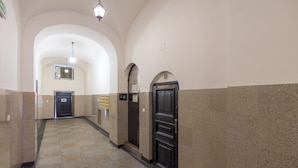 A hallway with a checkered floor, arched ceilings, and a door with a sign. - Old Town Grey Apartment (Warszawa)