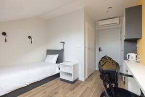 Relax in a stylish room with a made bed, nightstand, and comfortable chair.