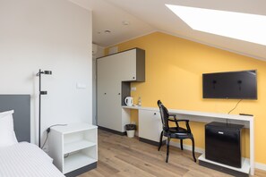 Enjoy a cozy retreat with a neatly made bed, desk, and flat-screen TV in this compact hotel room.