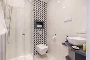Enjoy a refreshing shower in the glass-enclosed shower with a handheld showerhead, a white toilet, and a large sink.