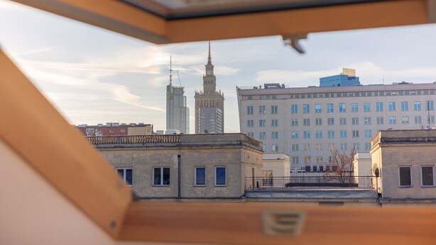 A view from a window overlooking a cityscape with a prominent tower and a large building with multiple windows. - ĄĘ Hostel Nowy Świat (Warszawa)