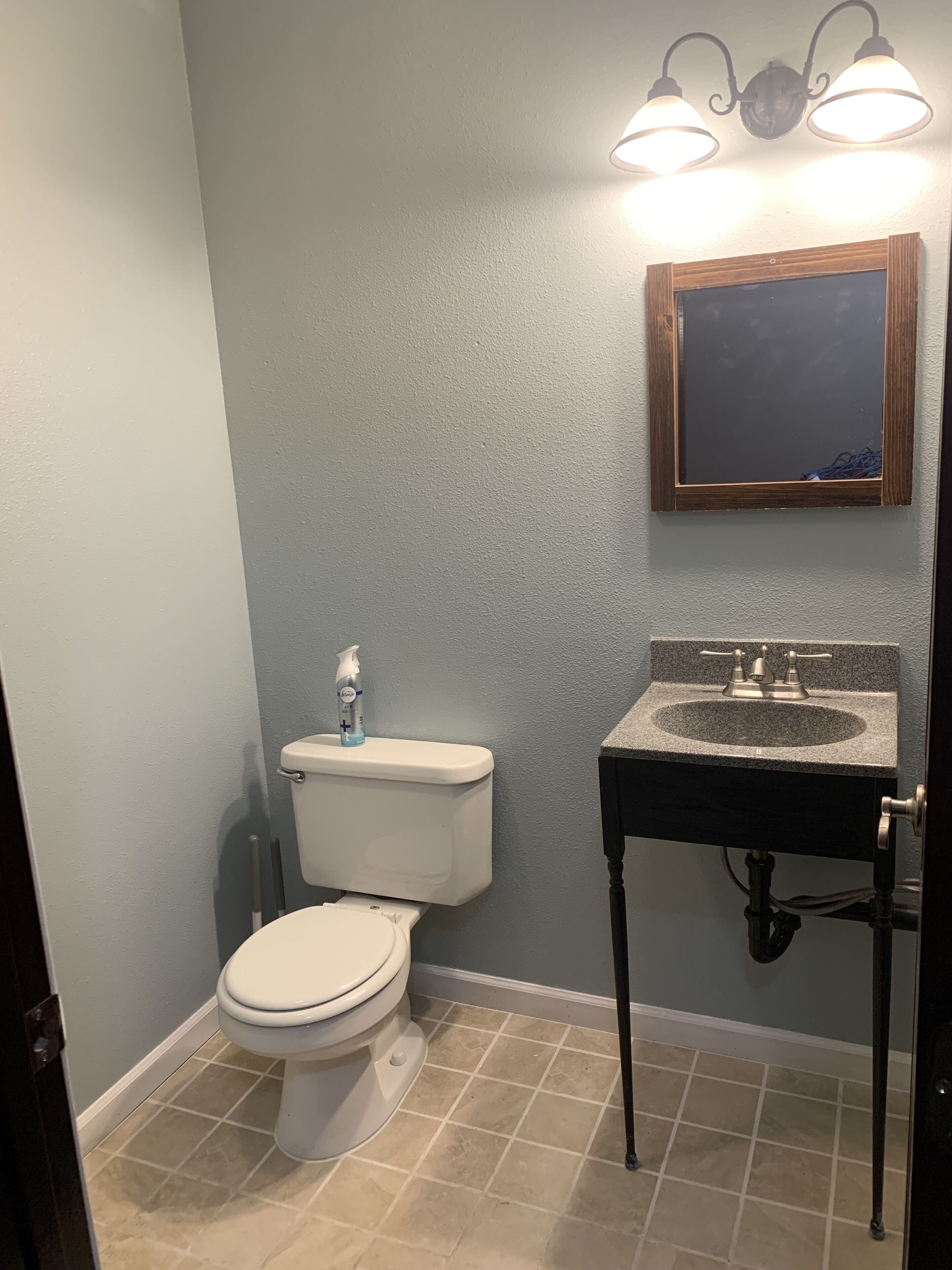 A bathroom with a toilet, sink, and mirror.