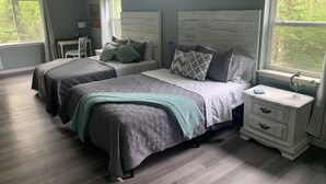 Une chambre avec deux lits, une table de chevet, une commode et de grandes fenêtres.
