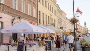 A street scene with outdoor cafes, a chalkboard menu, and pedestrians.