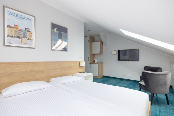 Una habitación de hotel con una cama, un escritorio, una silla, un televisor y un cuadro de Varsovia.