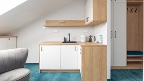 A compact kitchenette with a countertop, cabinets, and a window above.