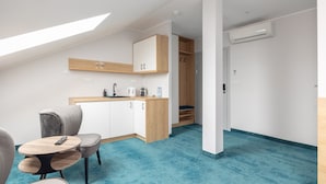 A modern, compact room with a kitchenette, a dining area with a table and chairs, and a built-in wardrobe.