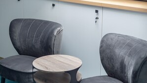 Une pièce moderne avec deux fauteuils gris à revêtement en tissu, une table ronde en bois et une lucarne au plafond.