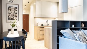 A modern kitchen with a dining area, a sofa, and a decorative plant. - Arkadia Prime Apartament (Warszawa)