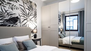 A bedroom with a bed, nightstands, a wardrobe, and a large window with curtains. - Arkadia Prime Apartament (Warszawa)