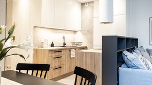 A modern kitchen with wooden cabinets, a black countertop, and a built-in bookshelf. - Arkadia Prime Apartament (Warszawa)