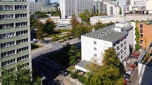 Un edificio alto con varios pisos, rodeado de otros edificios y árboles.