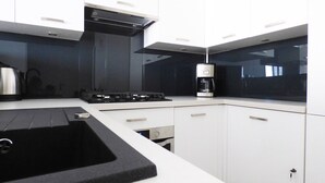 Una cocina moderna con gabinetes blancos, encimera negra y electrodomésticos de acero inoxidable.