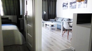 Un espacio habitable moderno y funcional con cama, sofá, mesa de comedor y televisor.