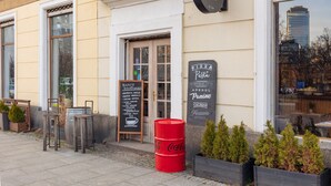 Ein Restaurant mit Außenbereich, einem Coca-Cola-Fass und einer Speisekarte, die Pizza und Pasta anbietet.