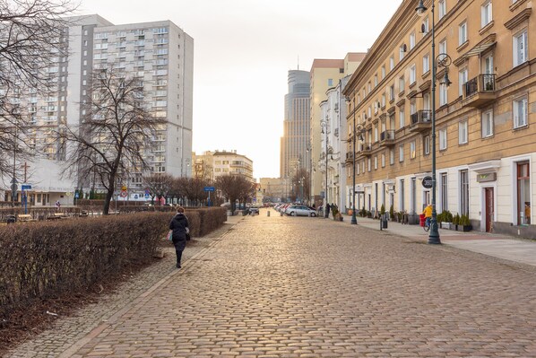 A cobblestone street lined with multi-story buildings, some with balconies and large windows.