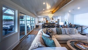A spacious living area with a large sofa, a dining table, and a kitchen in the background. - Lake Oconee lake front with pool (Eatonton)
