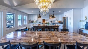 A spacious kitchen with a large island, modern appliances, and a chandelier. - Lake Oconee lake front with pool (Eatonton)