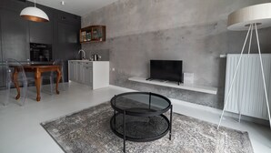 Une cuisine moderne avec un coin repas, un téléviseur et une table ronde surmontée d’un tapis.