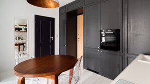 Une cuisine moderne avec des meubles de couleur sombre, une table à manger en bois et un luminaire suspendu.