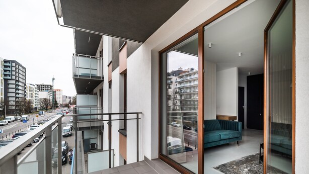 Un appartement moderne doté d’un balcon, de grandes fenêtres et offrant une vue sur la ville.
