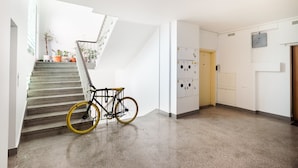 A staircase with a bicycle parked at the bottom, a set of lockers, and a door with a sign. - City Centre Open View Apartment (Warszawa)