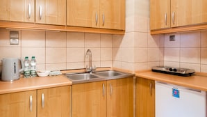 A kitchen with wooden cabinets, a sink, a stove, and a refrigerator. - City Centre Open View Apartment (Warszawa)