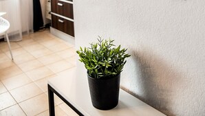 A modern interior with a wall-mounted sign reading "crest," a potted plant, and a dining area with a table and chairs. - Saska Kępa Malachite Studio (Warszawa)